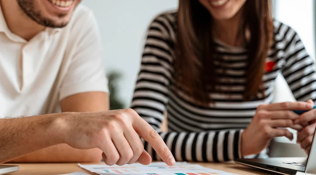 A man and woman are reviewing a laptop screen, discussing options for a small personal loan.