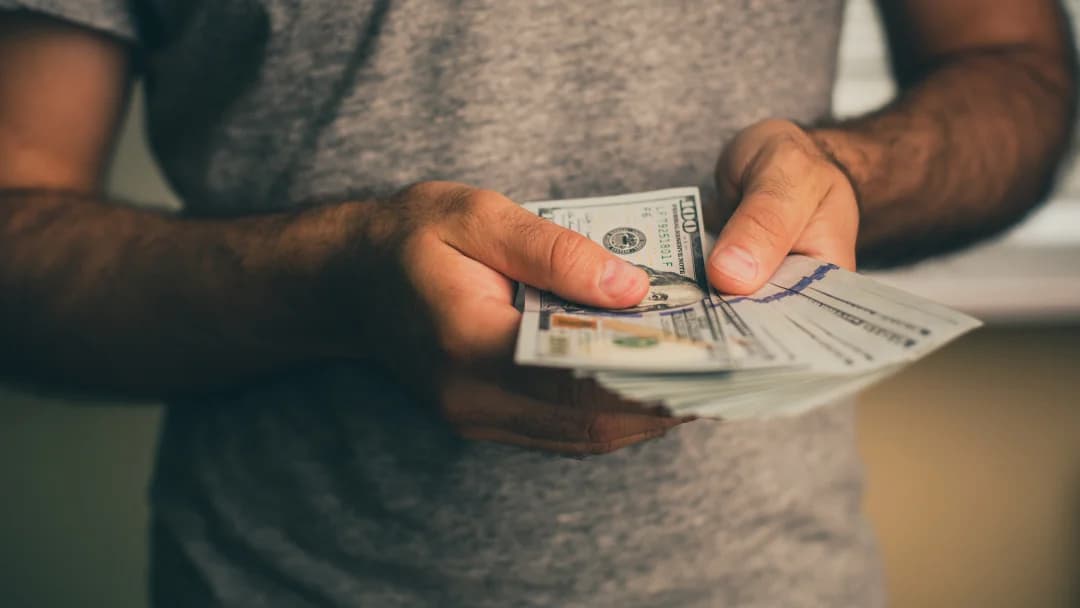 A man holding a stack of cash, symbolizing loan repayment.