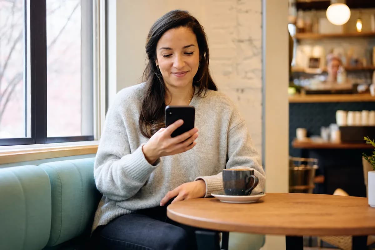 Young woman in a cafe checking her phone after applying for a short-term instalment loan online