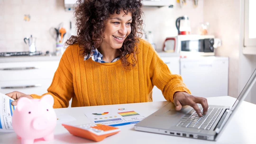 A woman uses her laptop while seated at a table, illustrating a productive work environment.