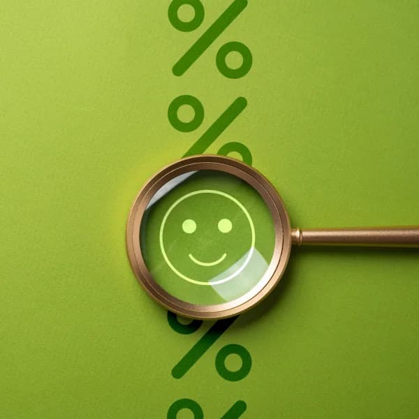The image shows a magnifying glass with a percentage symbol and a smiling face on a green background, symbolizing a good credit rating.